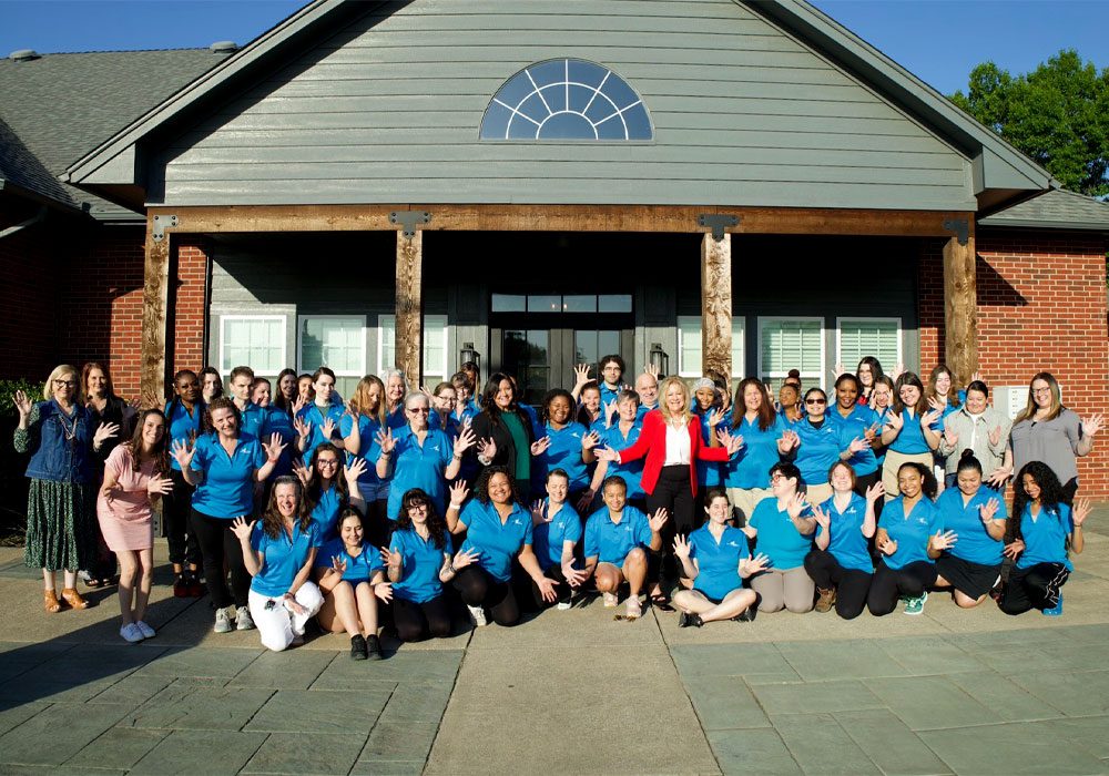image of Debbie and the full Buckets and Bows team, posed in front of a building.